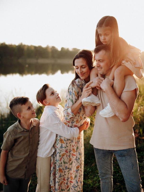 Une famille à AValon Chalet, les gets été, parents, un enfant sur le dos et deux garçons près d'un lac. 